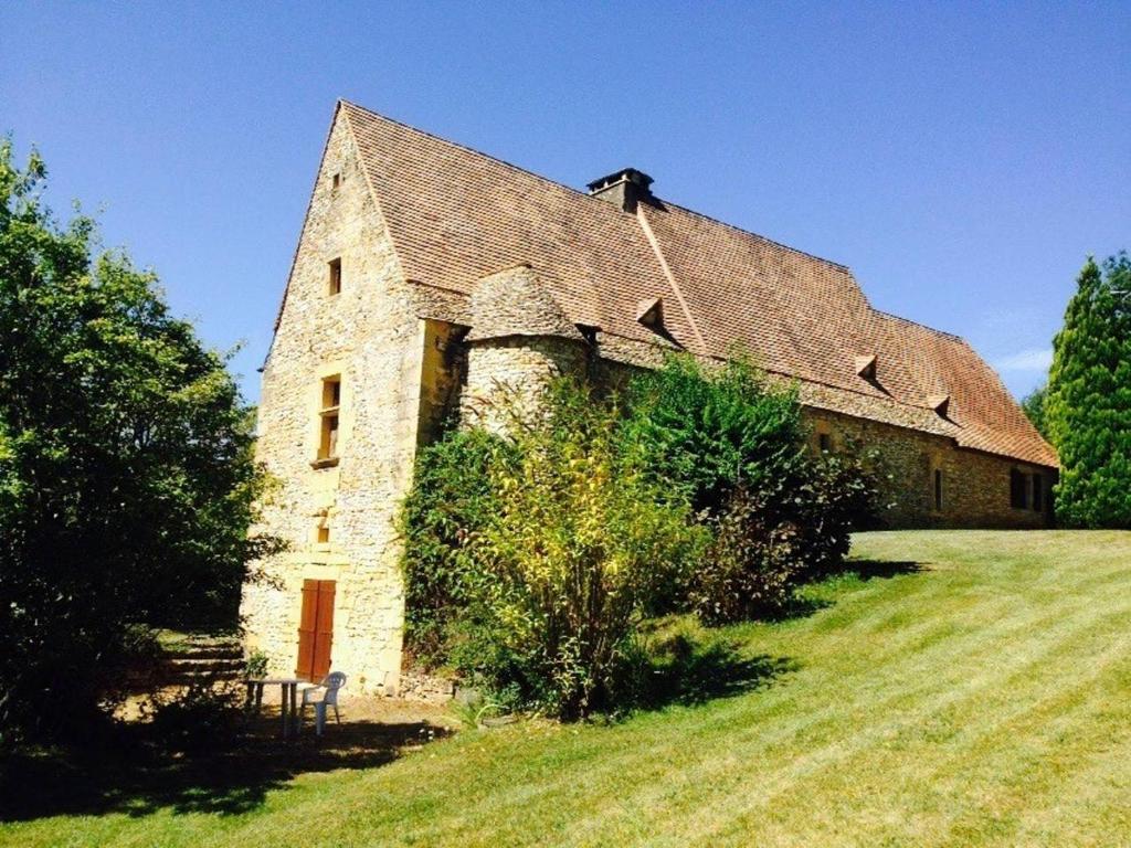 un ancien bâtiment en pierre avec un toit sur un champ dans l'établissement Studio dans Maison forte, 8km Sarlat, à Saint-André-dʼAllas