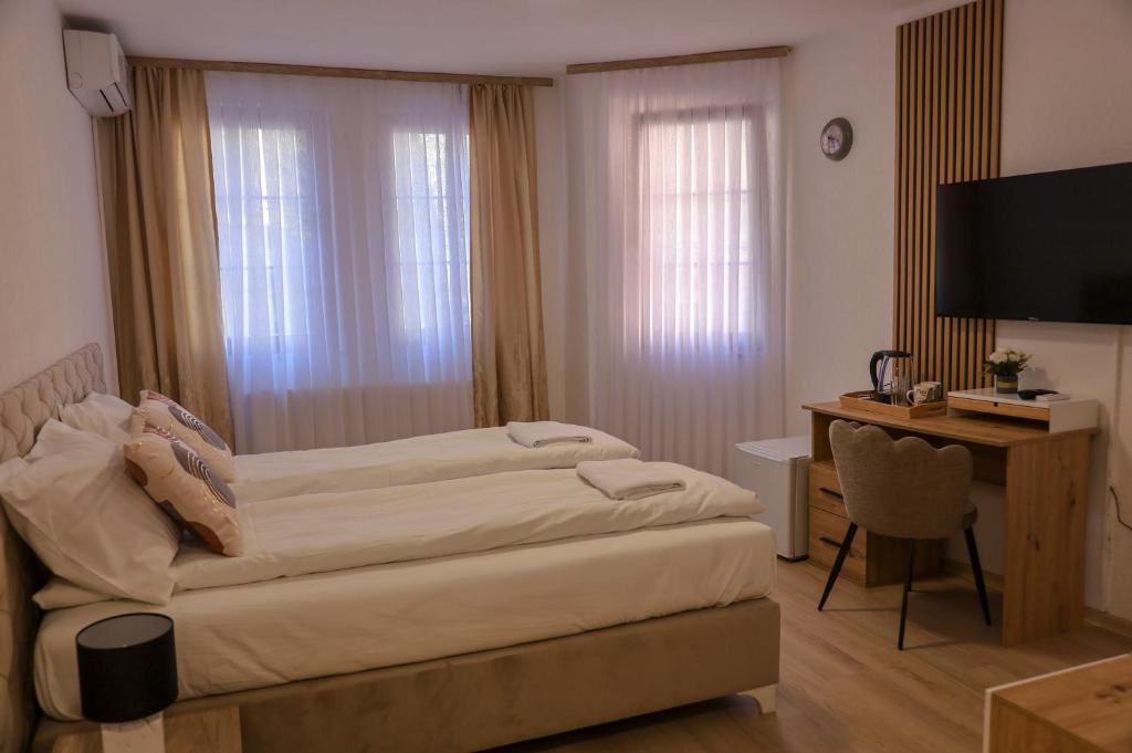 a bedroom with two beds and a desk and a television at Careva Cuprija Apartment&Rooms in Sarajevo