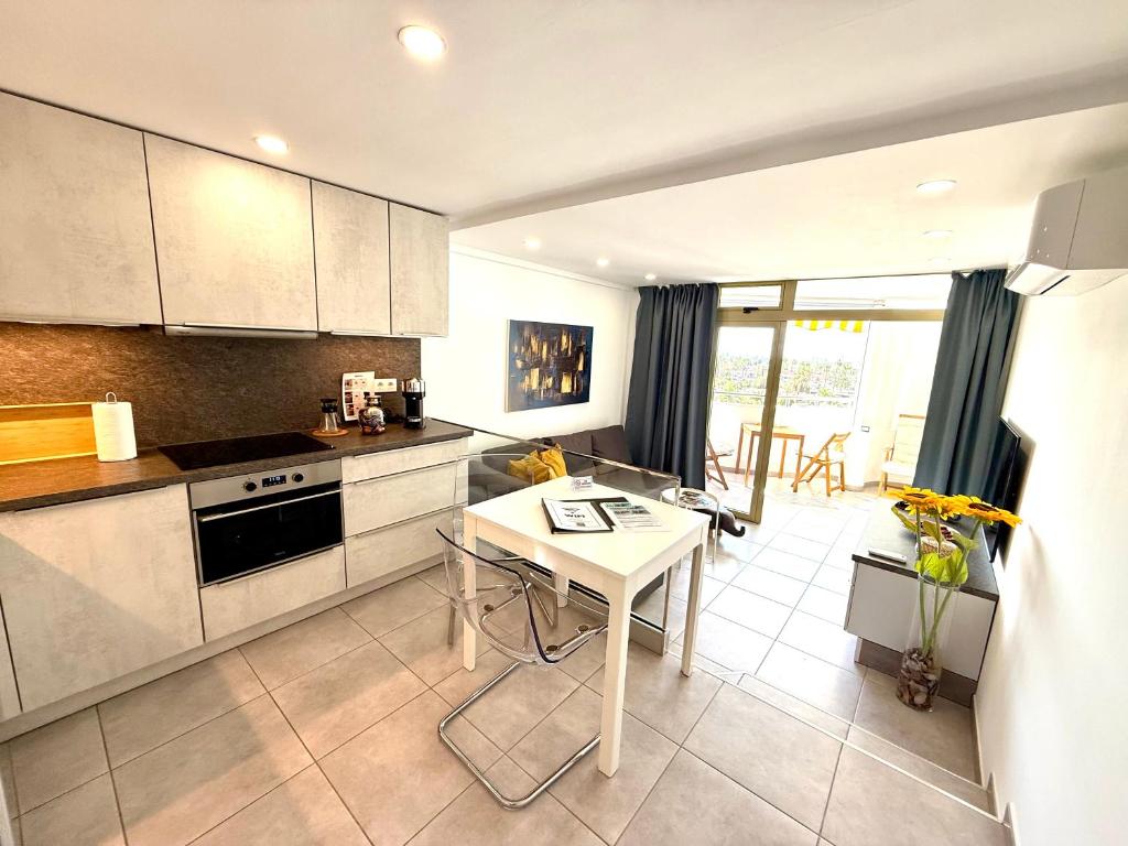 a kitchen with white cabinets and a table in it at Exclusive Holiday - Edifico Paraiso Maspalomas in San Fernando