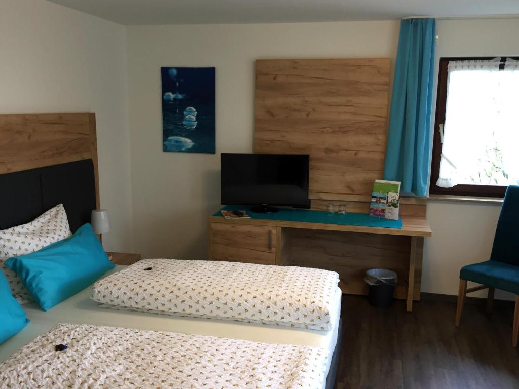 a bedroom with two beds and a desk with a television at Gästehaus Meng in Bad Krozingen