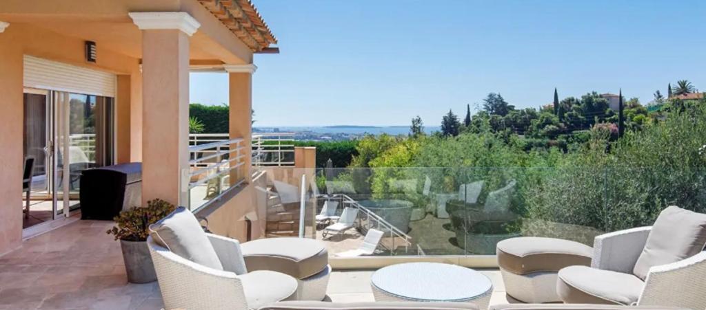 d'une terrasse avec des chaises blanches et d'un balcon avec vue. dans l'établissement Villa vue mer Mandelieu 4 chambres, à La Celle-sous-Gouzon
