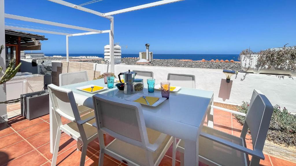 a white table and chairs on a balcony with the ocean at Caideros Sunset in Los Caideros