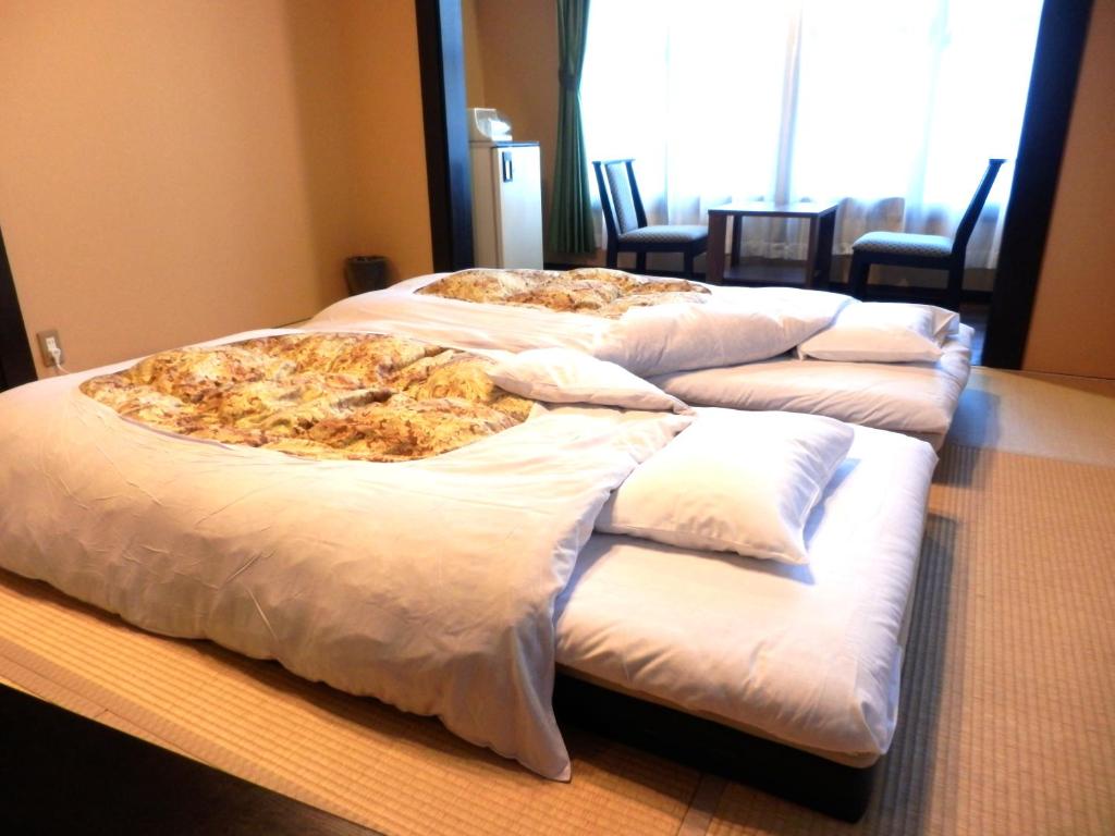 un groupe de quatre lits avec une pizza dessus dans l'établissement Tenryuso, à Ōtaki