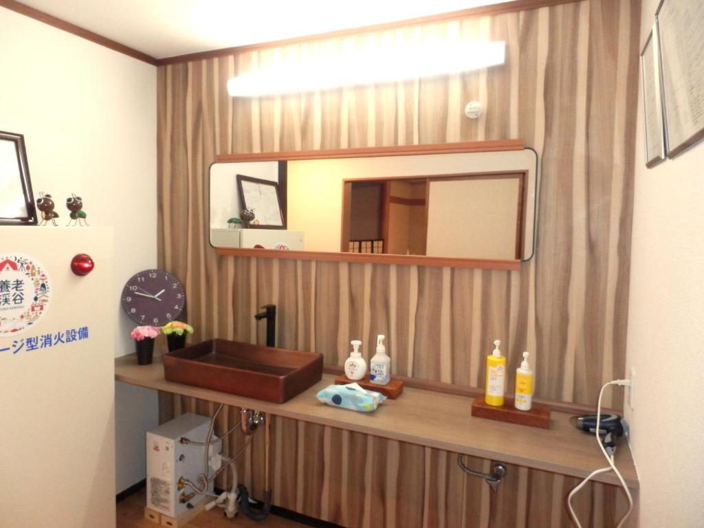 La salle de bains est pourvue d'un miroir et d'un mur en bois. dans l'établissement Tenryuso, à Ōtaki