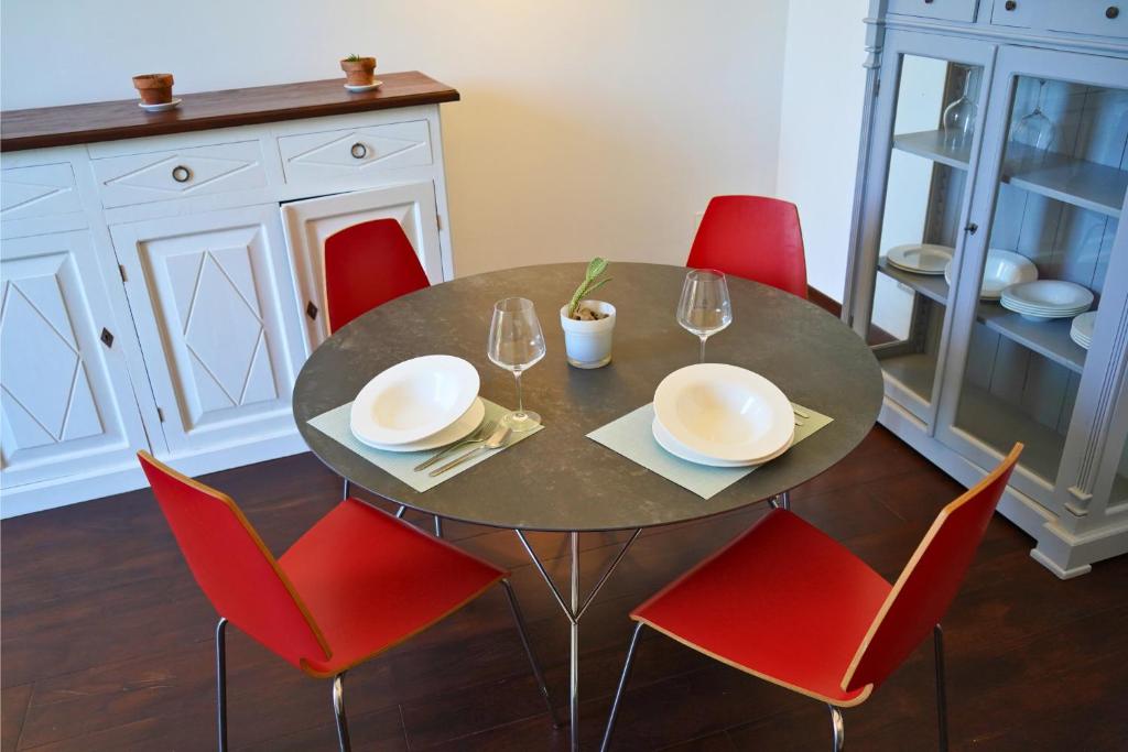 un tavolo da pranzo con sedie rosse e un tavolo con bicchieri di Lumiae Suite a Lecce