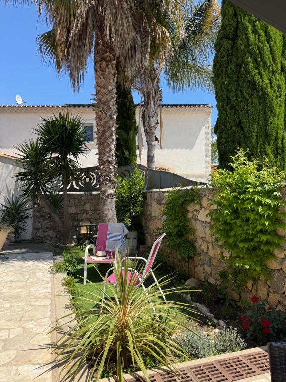 a patio with a pink chair and palm trees at chez Maël in Le Muy