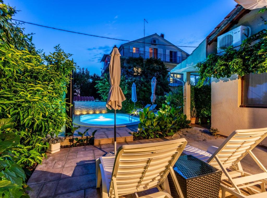 a patio with two chairs and an umbrella and a pool at Holiday Home Regina in Brodarica