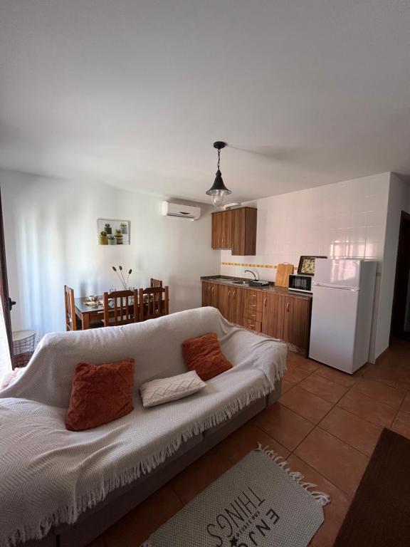 a living room with a white couch and a kitchen at Apartamentos turísticos Rutas del Torcal 1A in Villanueva de la Concepción