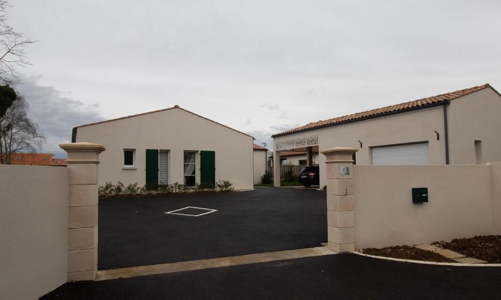 une maison blanche avec un portail et un parking dans l'établissement La bourbonnaise, à Corme-Royal