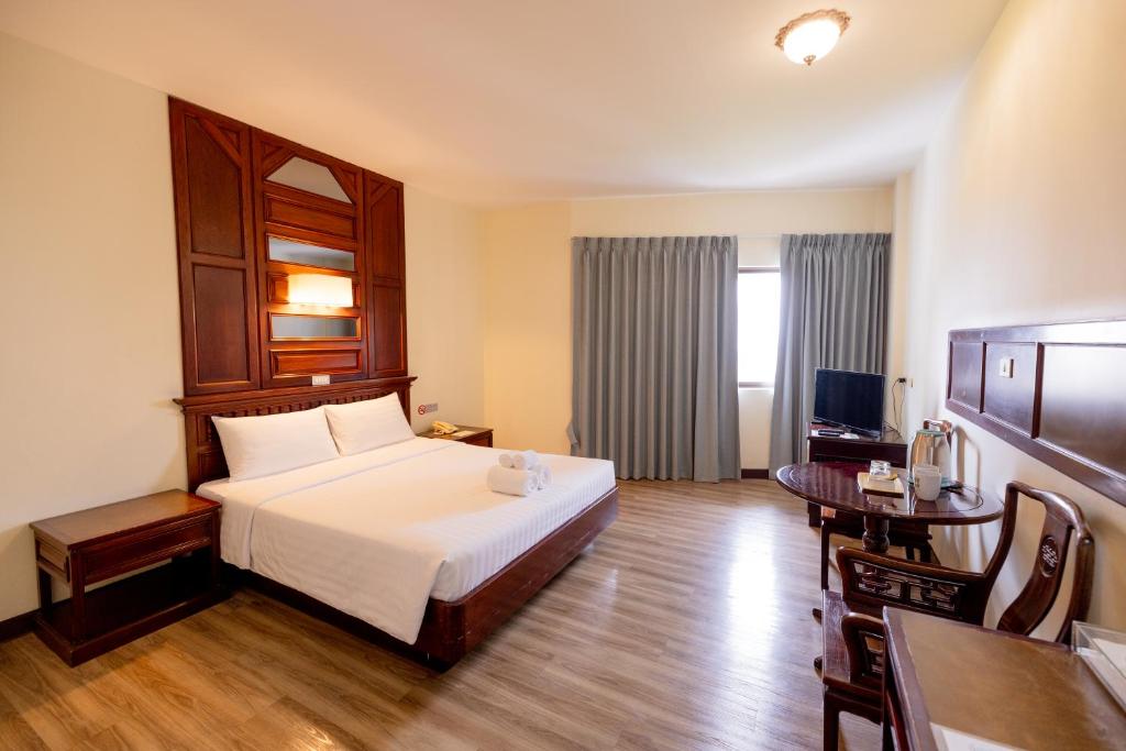 A traditional-style double room with a compact table, drink station, and curtained window.
