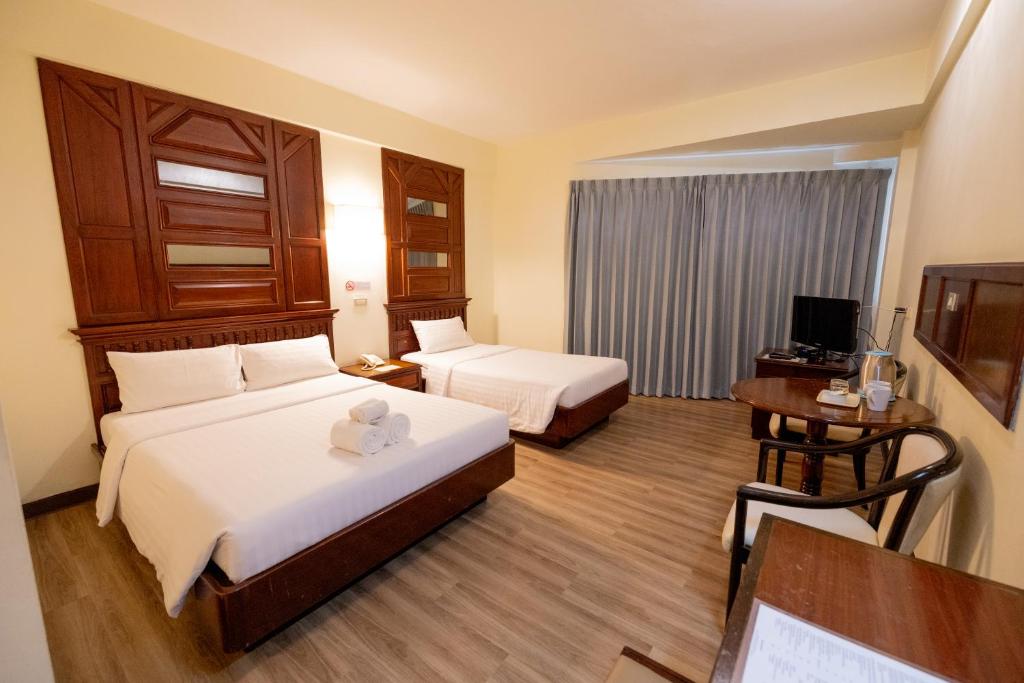A twin room with two beds, a curtained window, and a small table-and-chair area.