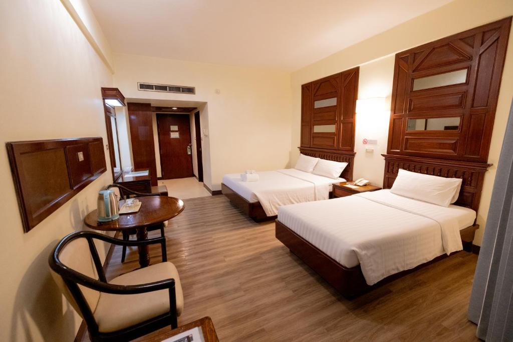 A twin room with two separate beds, a round table, and a compact drink station.