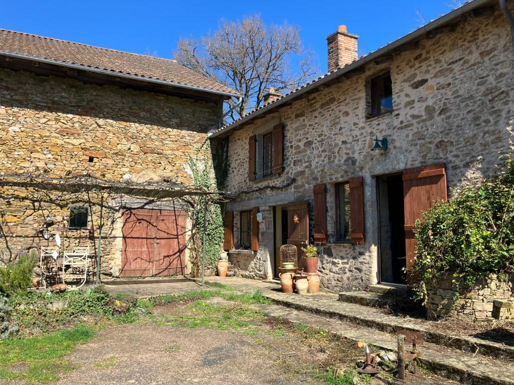 an old stone building with a red door on it at La Maison de la Treille in La Chapelle-Montbrandeix