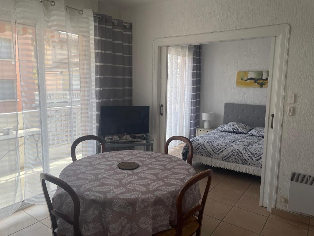 Cette chambre comprend une table, un lit et une fenêtre. dans l'établissement Studio à Sanary-Sur-Mer avec balcon à 200m du port, à Sanary-sur-Mer