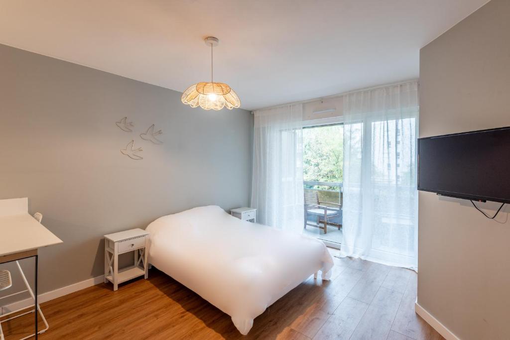 une chambre blanche avec un lit et une télévision dans l'établissement M40 Joli studio au calme, à Annemasse