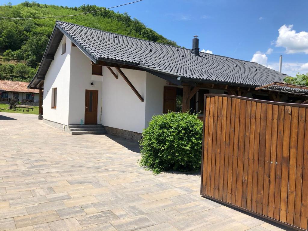a house with a wooden fence in front of it at Casuta de sub deal in Tăuţi