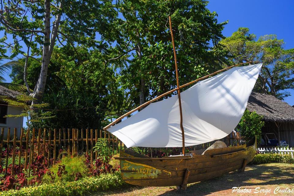 a wooden boat with a sail sitting in a yard at La Table d Alexandre Gîte de charme entre mangrove et mer in Hell-Ville