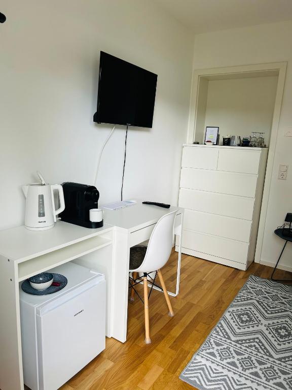 a white desk with a computer and a tv on a wall at Deluxe in Burladingen