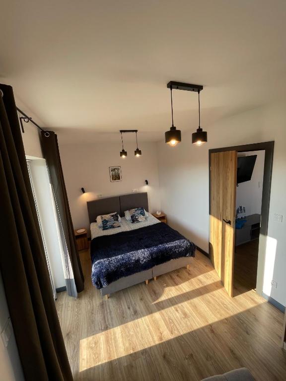 a bedroom with a bed and a mirror and lights at Apartamenty Łuska w Dębinie in Debina