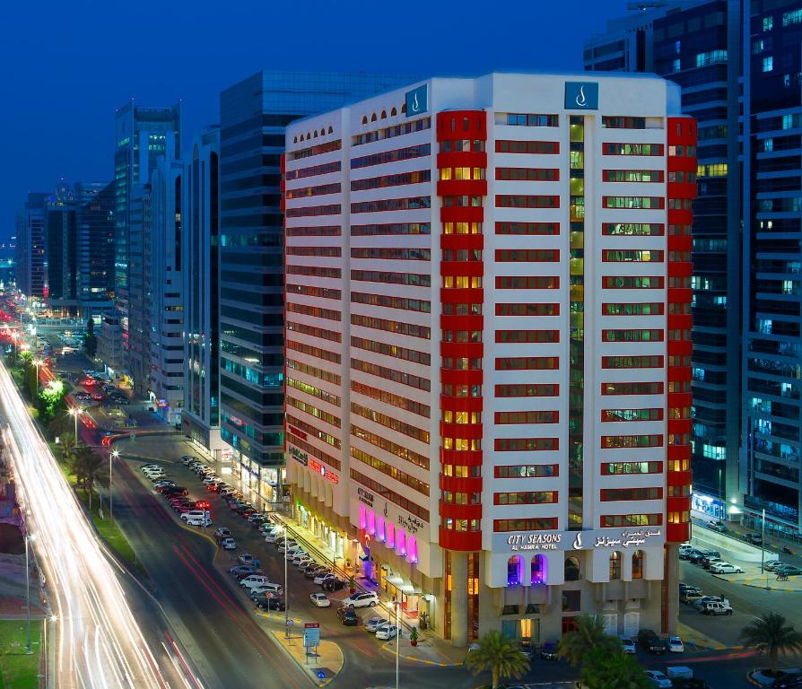 a tall red and white building on a city street at City Seasons Al Hamra Hotel in Abu Dhabi