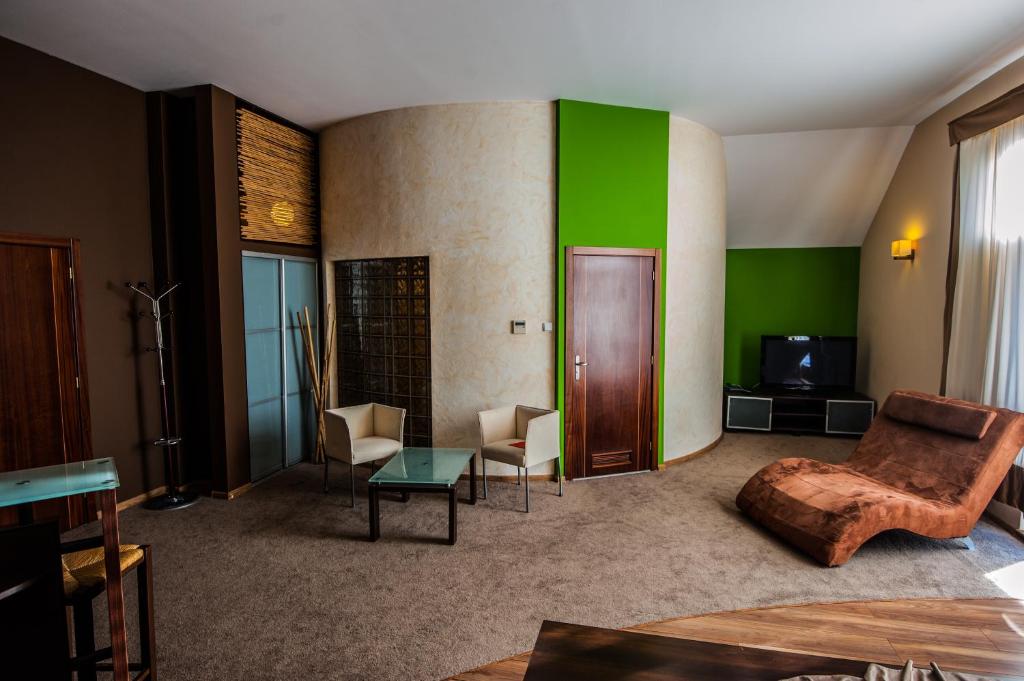 a living room with green walls and a couch and chairs at Hotel SenS in Mierzyn