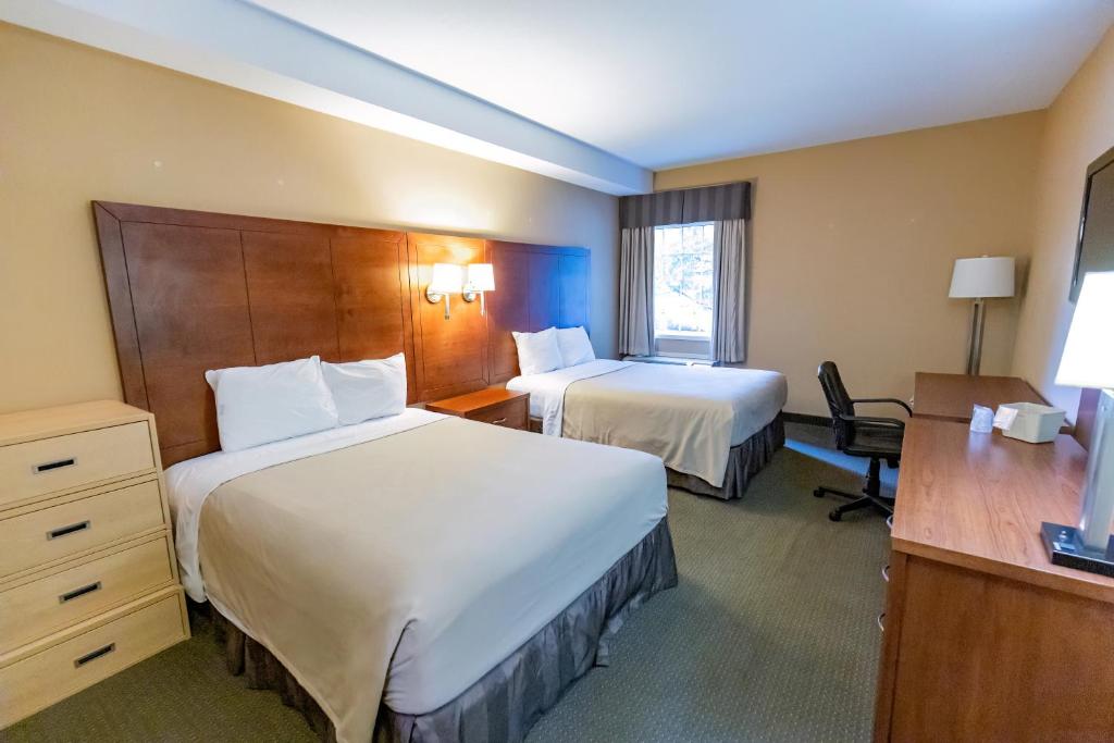 ein Hotelzimmer mit zwei Betten und einem Schreibtisch in der Unterkunft Gordon Hall Residence in Guelph