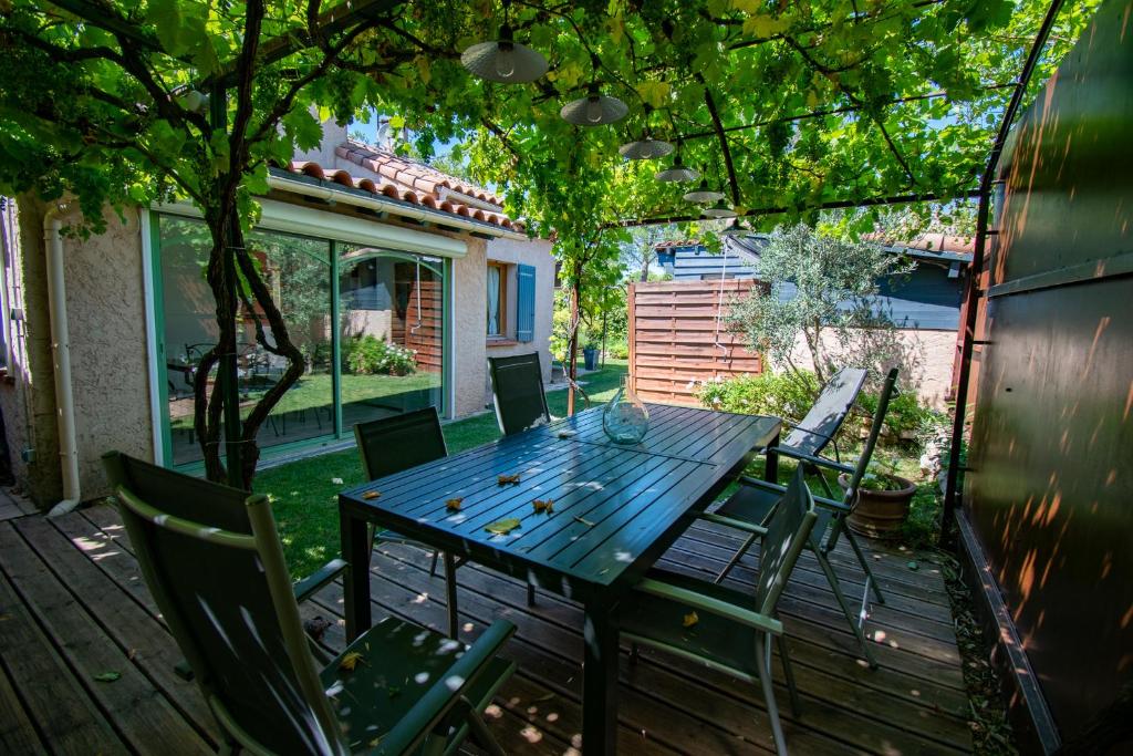 une table et des chaises en bois sur une terrasse dans l'établissement Jolie maison indépendante avec jardin et piscine, à Aix-en-Provence