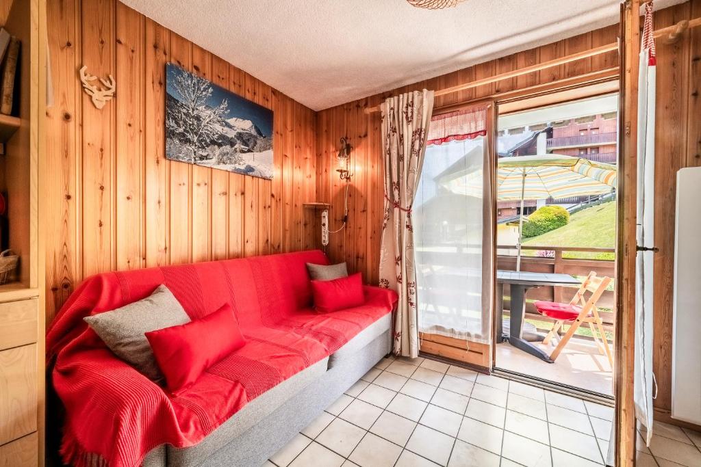 a red couch in a room with a window at Appartement les Oursons in Morillon