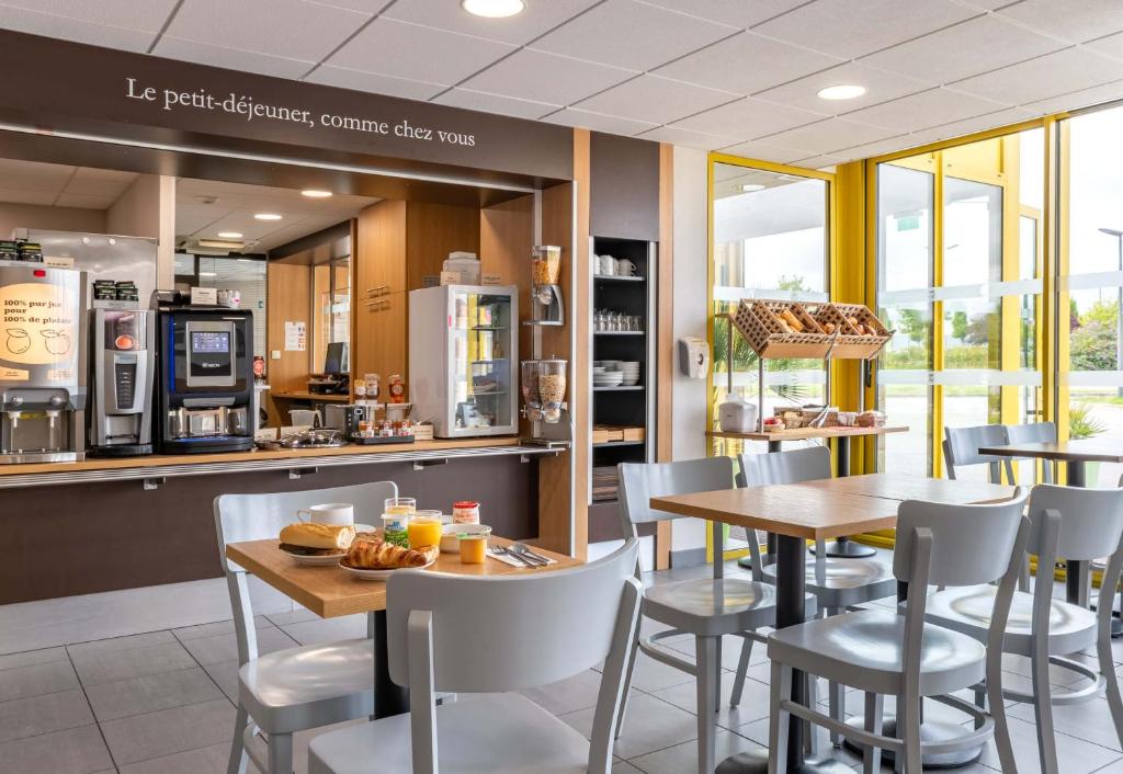 ein Restaurant mit Tischen, Stühlen und einer Theke in der Unterkunft B&B HOTEL Yvetot in Yvetot