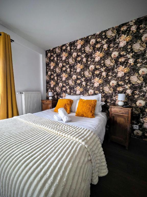 a bedroom with a bed with a floral wall at Le Clos des Roses in Pérouges