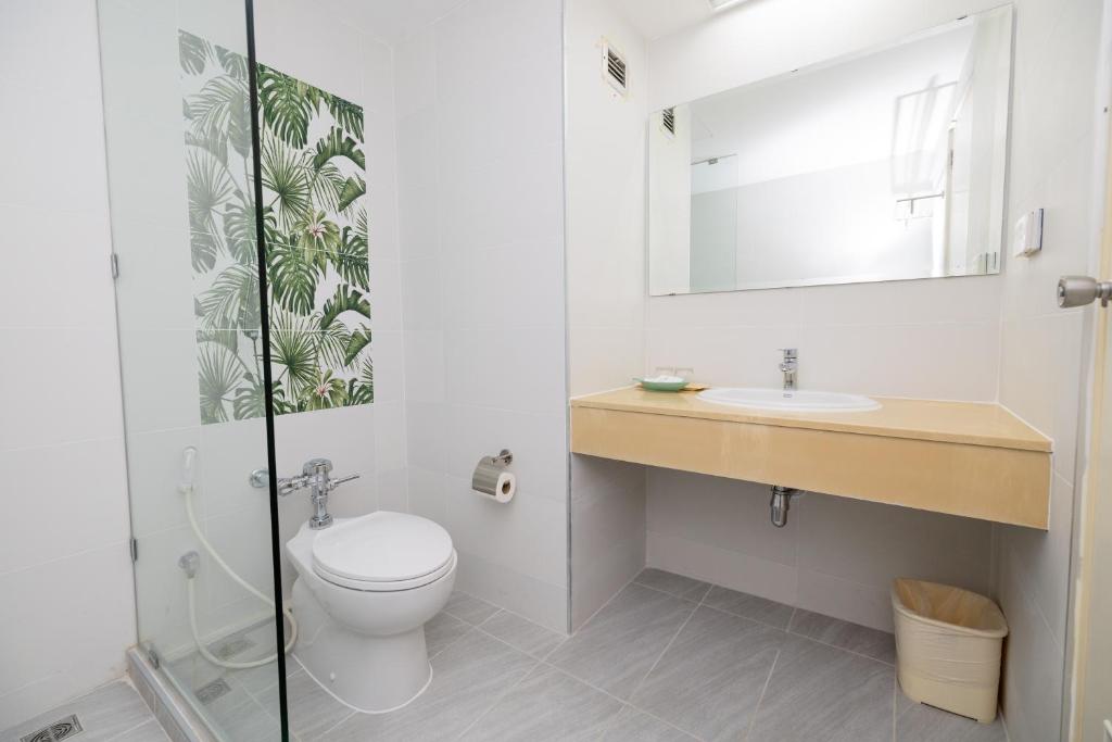 A compact bathroom with a toilet, glass-partitioned shower and vanity.