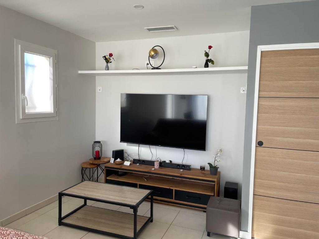 un salon avec une télévision à écran plat sur un mur dans l'établissement Villa calme deux chambres proche de la mer tout confort, à Pinet