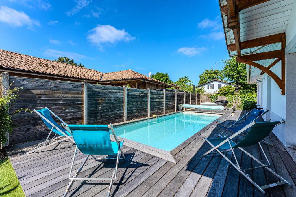 una terrazza con 2 sedie e una piscina di La villa Sirelis piscine et spa a Gujan-Mestras