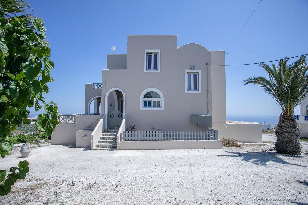 una casa bianca con una palma e l'oceano di Villa Anna with Panoramic sea views a Pyrgos