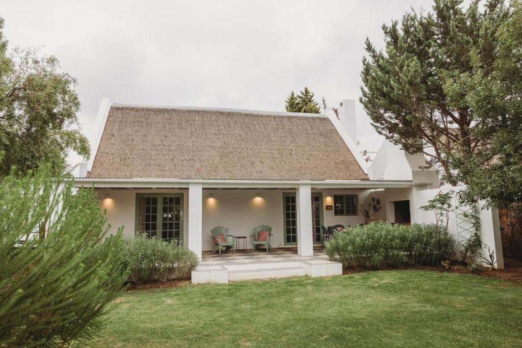 Cardigan Cottage في ماكغريغور: بيت ابيض وبه كراسي وساحة