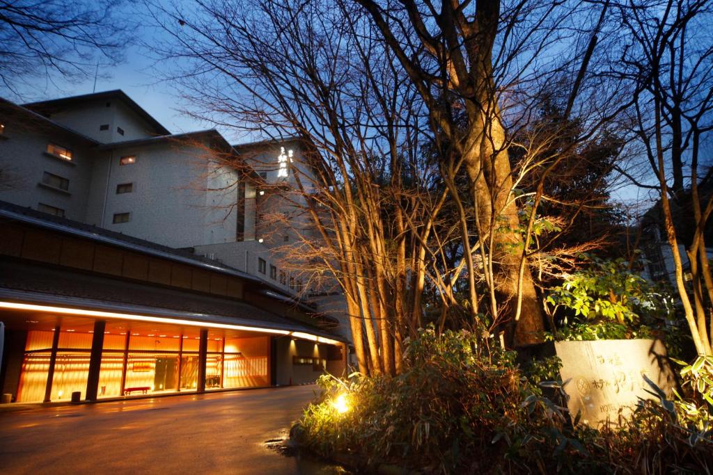 een gebouw met bomen voor een gebouw bij Kinosaki Onsen Nishimuraya Hotel Shogetsutei in Toyooka