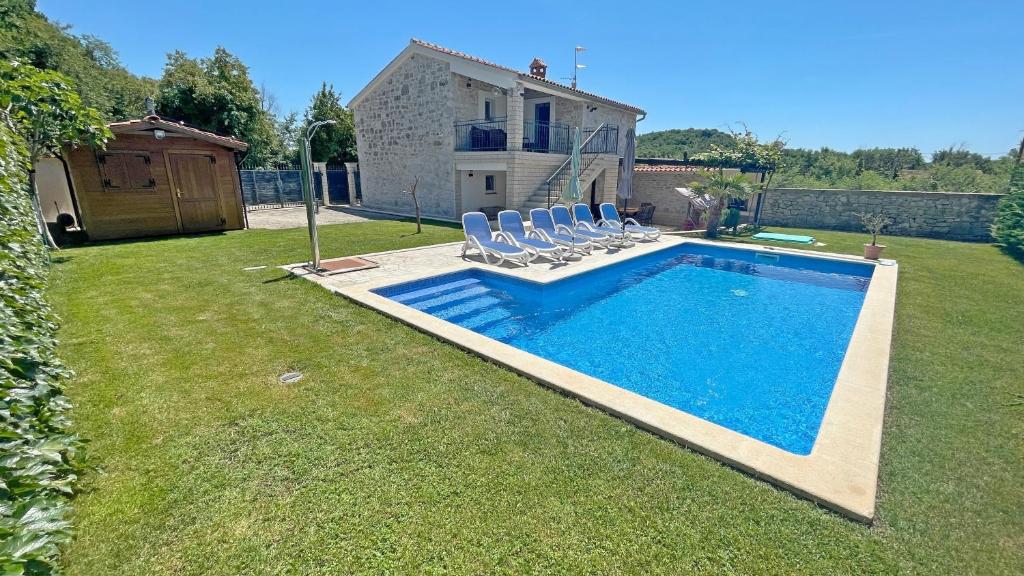 a backyard with a swimming pool with chairs and a house at Istrian stone Villa Lenny near Porec in Poreč