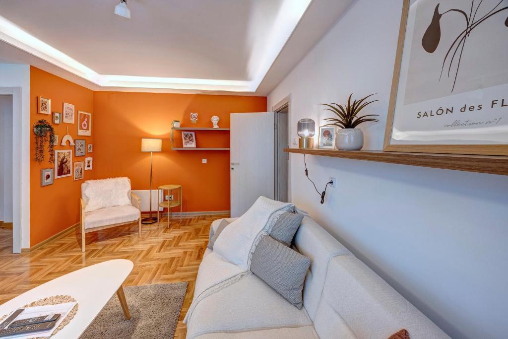 sala de estar con paredes de color naranja y sofá blanco en Marasca Belgrade - Cozy, Chic & Nomad-friendly Flat in Downtown, en Belgrado