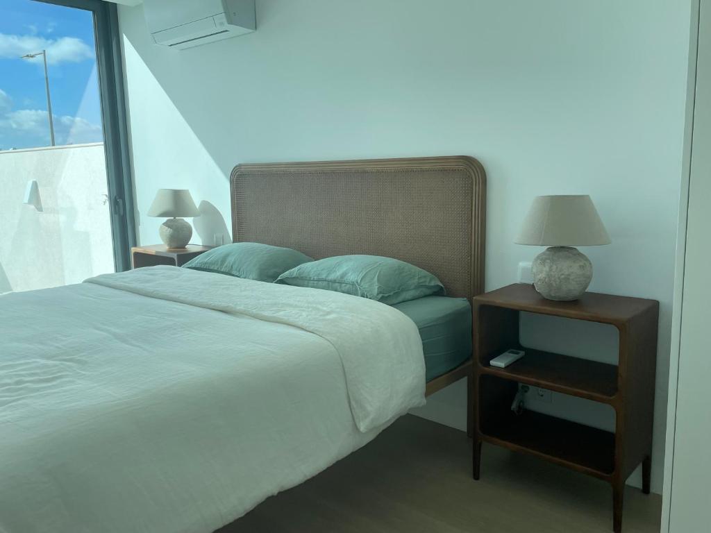 a bed with blue pillows and a night stand with a lamp at Lux Hiato's Villa in Luz de Tavira