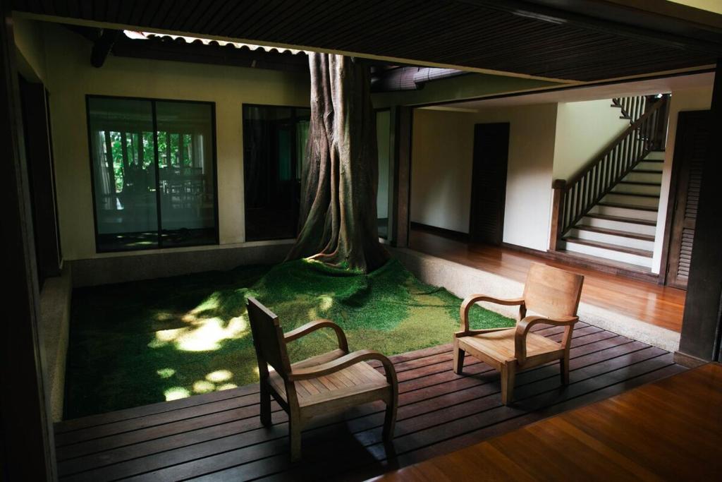 a house with two chairs and a tree on the porch at Pasir Hor Villa in Kota Bharu