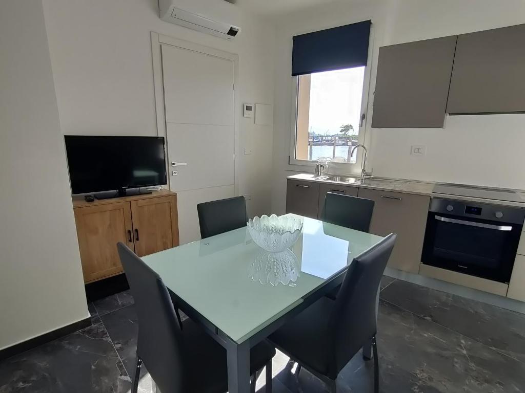 een keuken met een tafel met stoelen en een televisie bij Ca' Otto Velieri in Sottomarina