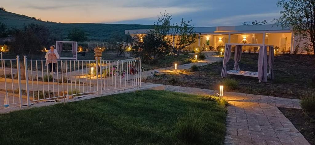 a woman standing next to a fence in a yard at night at Amarena Garden House in Matera
