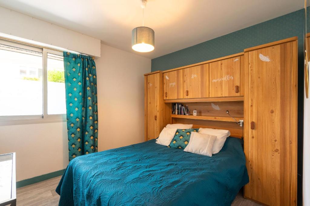 - une chambre avec un lit bleu et une armoire en bois dans l'établissement L'Echappée Royannaise, à Royan