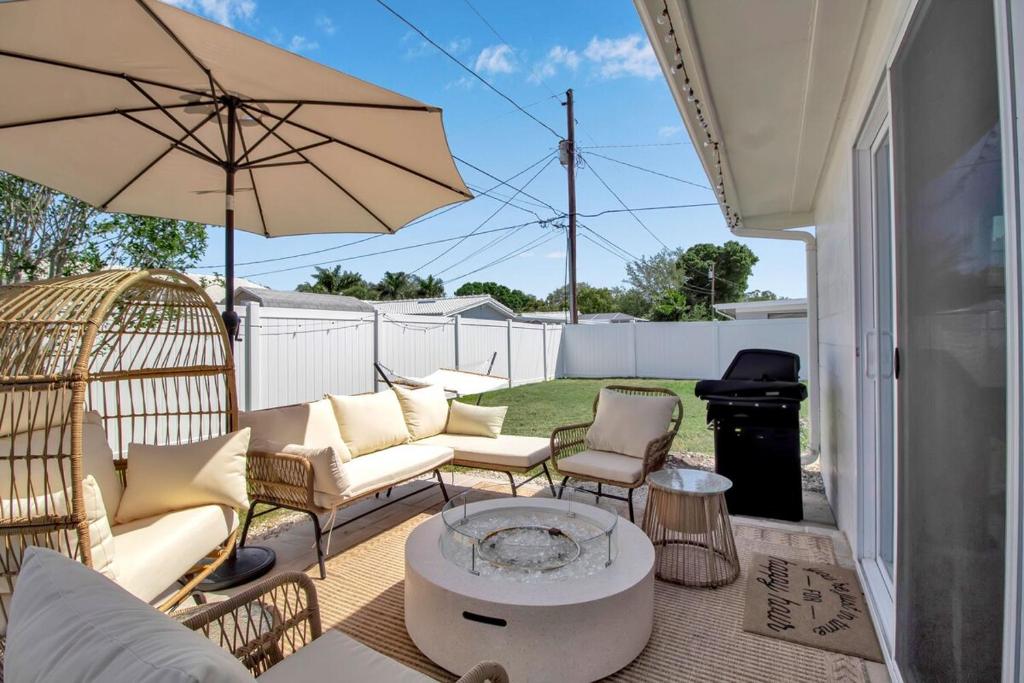 eine Terrasse mit Stühlen, einem Tisch und einem Sonnenschirm in der Unterkunft Madeira Beach Family & Pet Friendly Luxury Getaway in Seminole