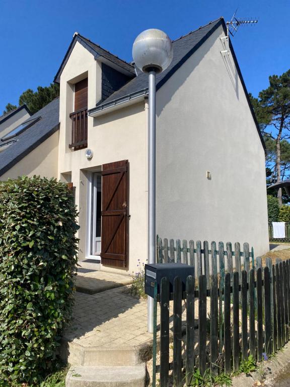 une petite maison blanche avec une clôture en bois dans l'établissement Maison à 100m de la mer, à Piriac-sur-Mer