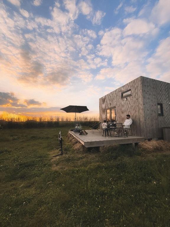 un groupe de personnes assises sur une terrasse avec un parasol dans l'établissement La Tiny House de l'Ouchette, à Brégy