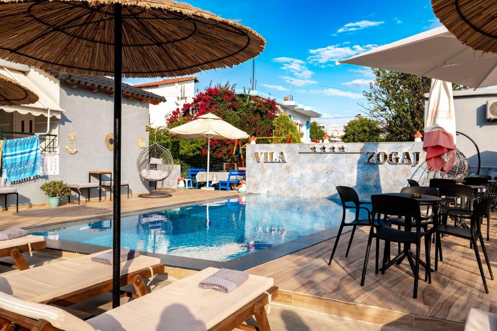 a pool with tables and chairs and an umbrella at Hotel Zogaj in Ksamil