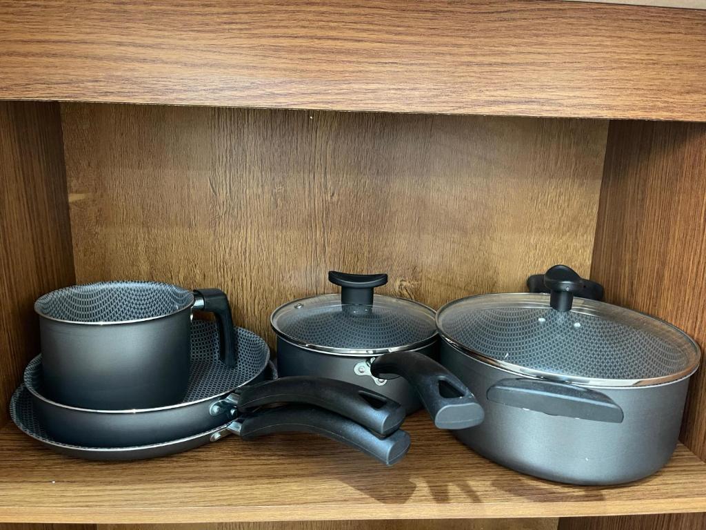 three pots and pans sitting on a shelf at Apartamento Completo in Botucatu