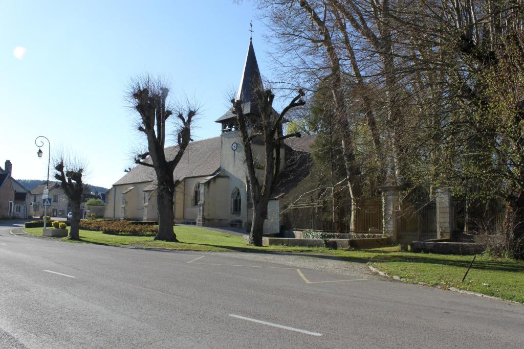 a church with a steeple on the side of a street at Charmante Maison Pierres 1768 in Polisy