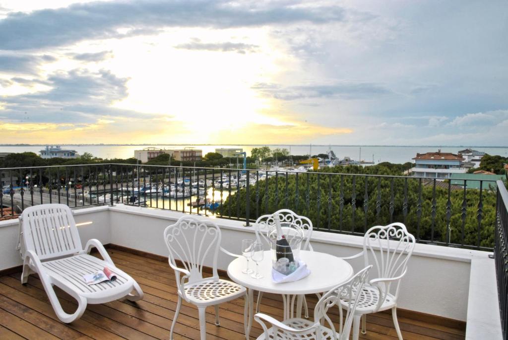 a balcony with a white table and chairs and the ocean at Hotel La Goletta in Lignano Sabbiadoro